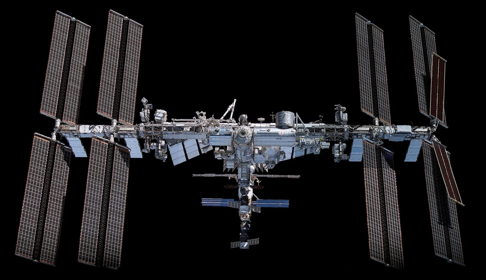 Station spatiale internationale avec ses longs panneaux solaires déployés, détachée sur fond noir.