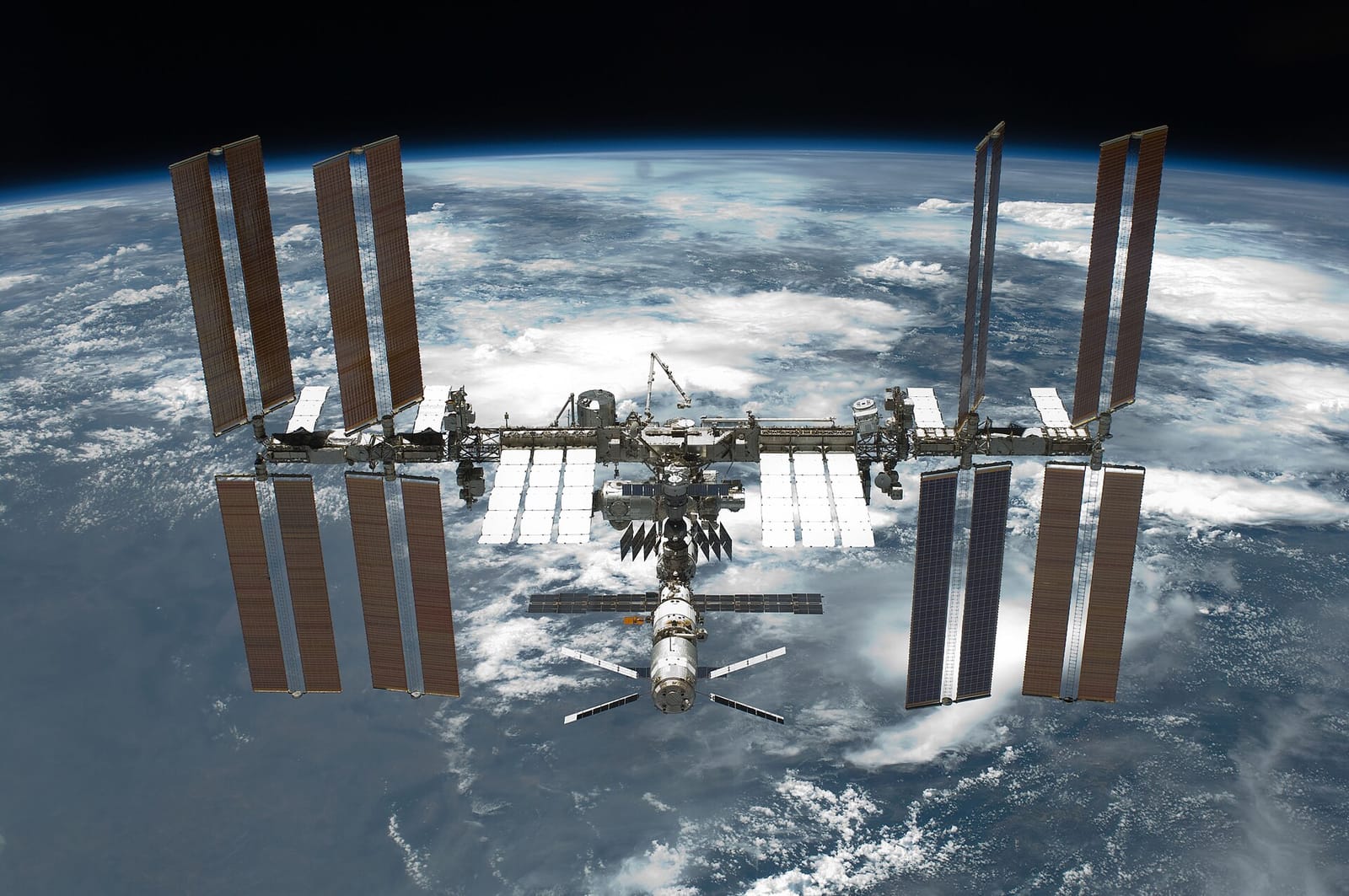 Station spatiale internationale survolant la Terre, avec ses panneaux solaires et ses modules métalliques.